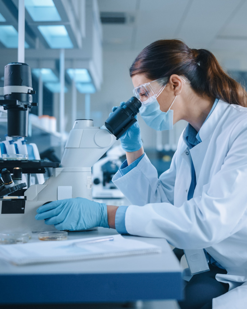A female person is working with a microscope in a laboratory.