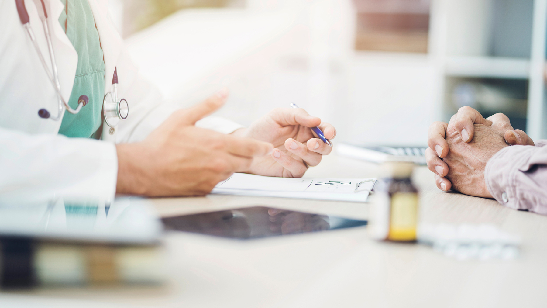 A doctor's hands during an informed consent discussion with a patient.